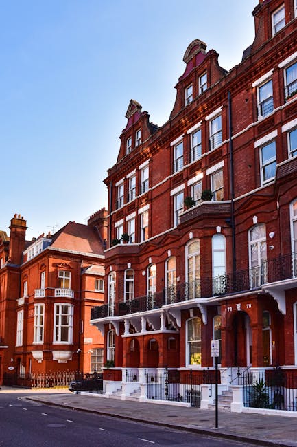 Close-up of a rectangular white street sign mounted on a red brick wall, displaying the text 'Welcome to South Kensington' with 'SW7' in the bottom right corner in red. The sign features black and red lettering and is secured with visible screws. The brick wall behind the sign shows a pattern of horizontal bricks with various shades of red and brown, indicating an outdoor setting typical of residential or commercial properties in London. This signage can be seen as part of the context for a house removal or home relocation service, such as those provided by Removal Van Kensington, highlighting the area where furniture transport and packing and moving operations might take place during a house move in South Kensington.